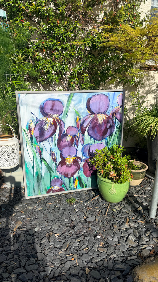 Painting of purple flowers on a gravel surface with plants around